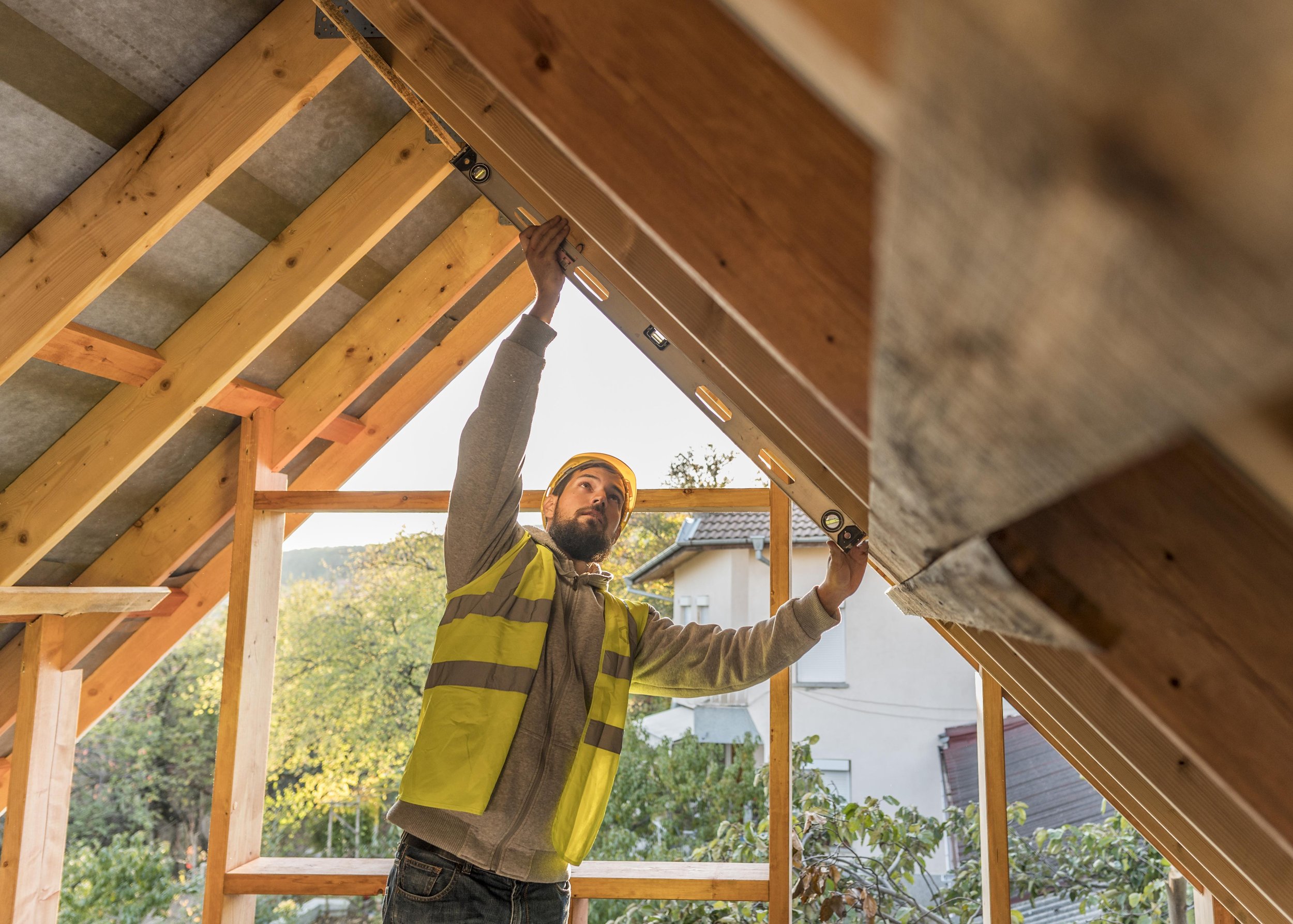 Man measuring roof structure in a construction setting, showcasing roofing work and inspection processes relevant to home maintenance and Pace Roofing services.